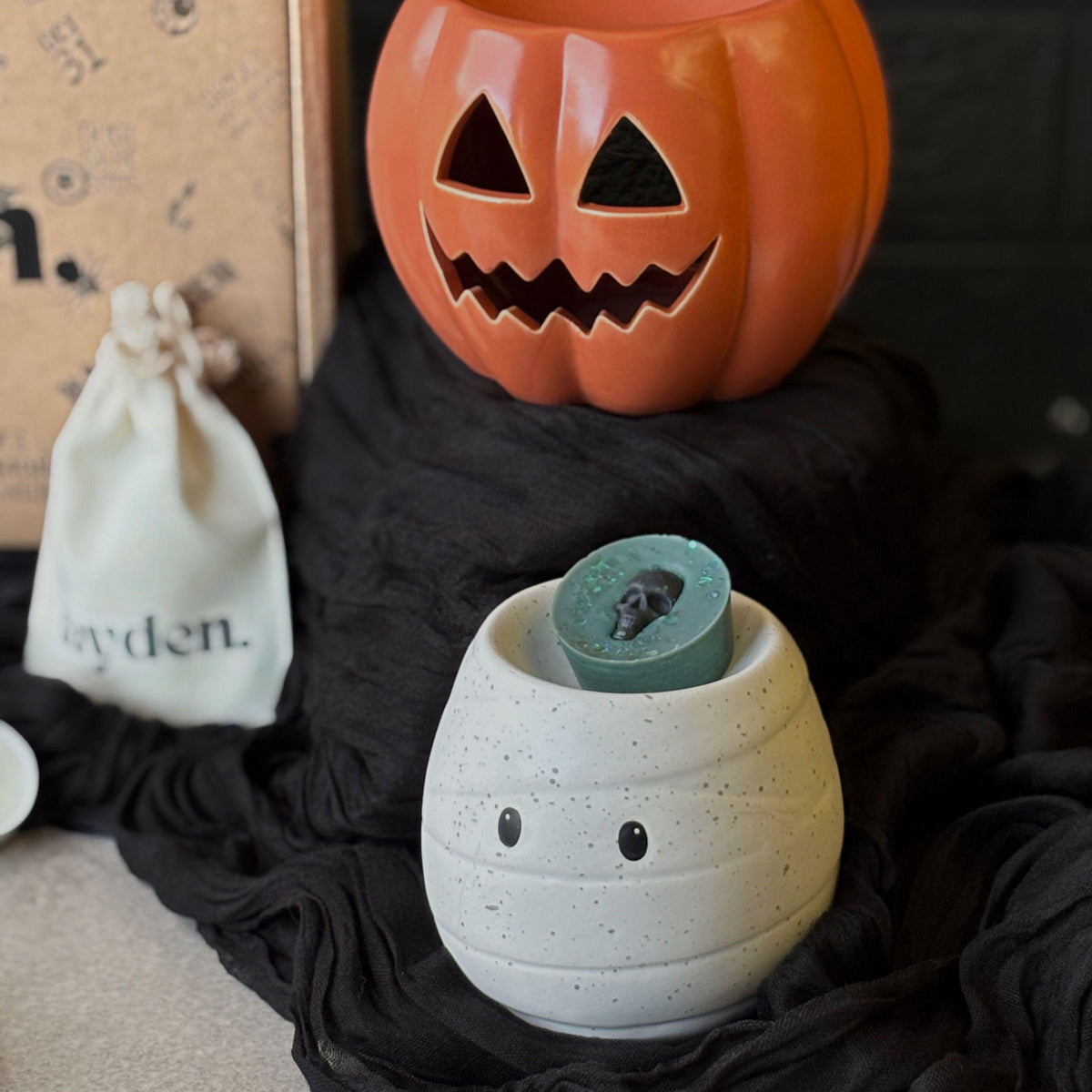 Halloween book stack wax melt burner styled with black fabric, showing a magical stack of orange, black and white book designs. A spooky ceramic oil burner for autumn home décor, cosy Halloween fragrance and wax melts.  Halloween Wax Melts
Hug In A Box Gifts
Boo Basket Gift Idea
Home Fragrance Gift
Halloween Wax Burner
Wax Melt Burners
Seasonal Oil Burners
Witchy Home Decor
Gothic Melt Burner
Ceramic Wax Burners
Pumpkin Wax Burner
Jack O Lantern
Spooky haunted House
