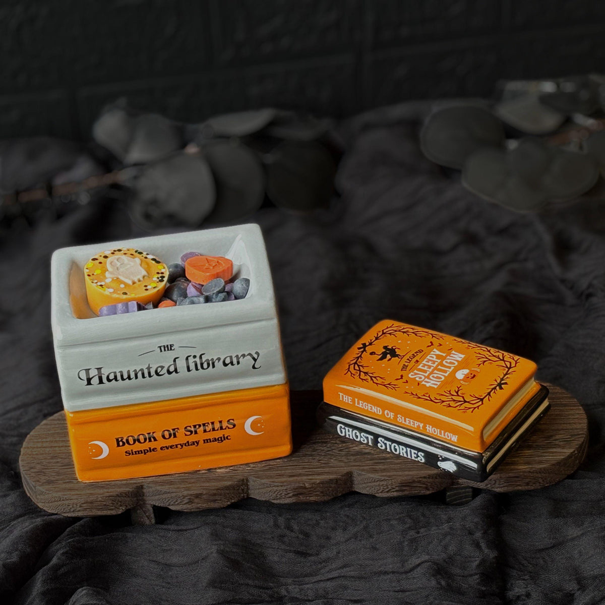 Halloween book stack wax melt burner styled with black fabric, showing a magical stack of orange, black and white book designs. A spooky ceramic oil burner for autumn home décor, cosy Halloween fragrance and wax melts.  Halloween Wax Melts
Hug In A Box Gifts
Boo Basket Gift Idea
Home Fragrance Gift
Halloween Wax Burner
Wax Melt Burners
Seasonal Oil Burners
Witchy Home Decor
Gothic Melt Burner
Ceramic Wax Burners
Pumpkin Wax Burner
Jack O Lantern
Spooky haunted House